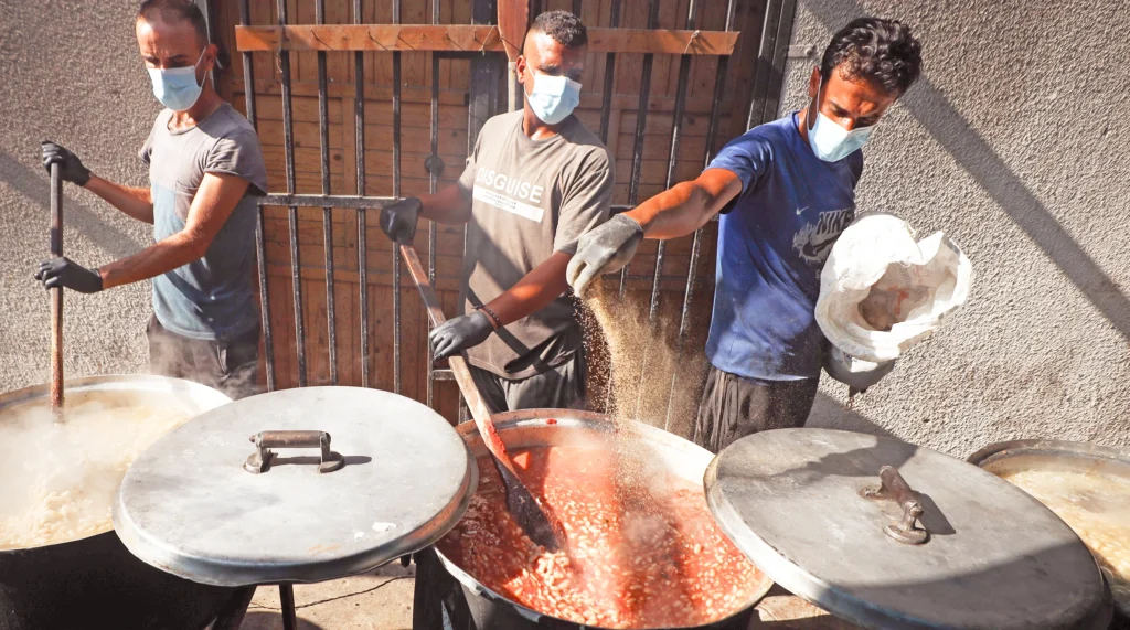 Funded by Christian Aid's partner CFTA, a team cook up nutritious meals of bean stew and rice for displaced people in the Khan Younis area of Southern Gaza.