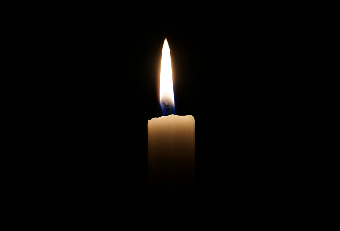 A single lit candle in the darkness