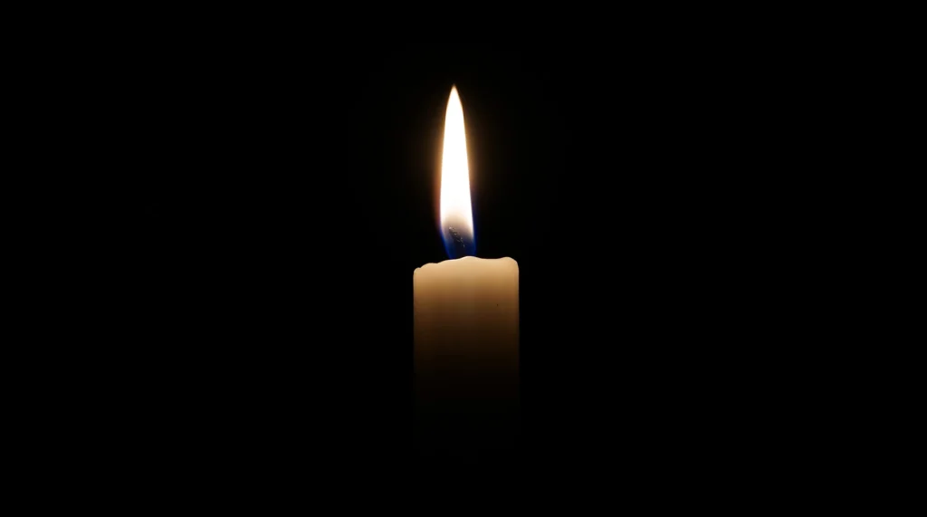 A single lit candle in the darkness