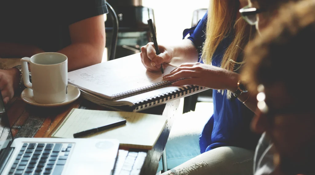 Photo shows a group of people working around a desk.